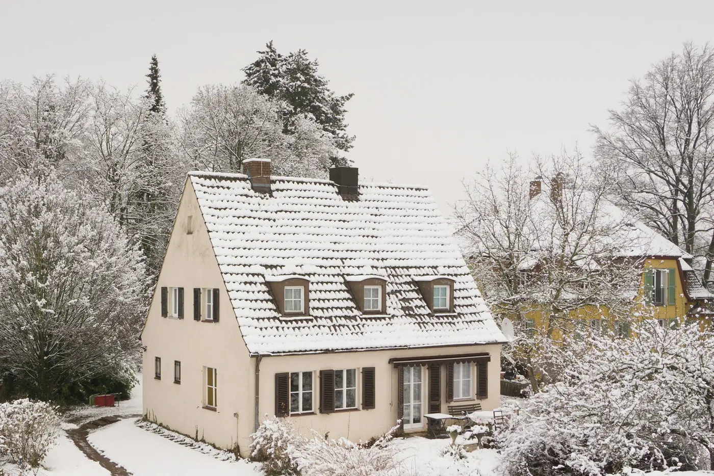 Verschneites Einfamilienhaus mit geräumtem Weg im Winter